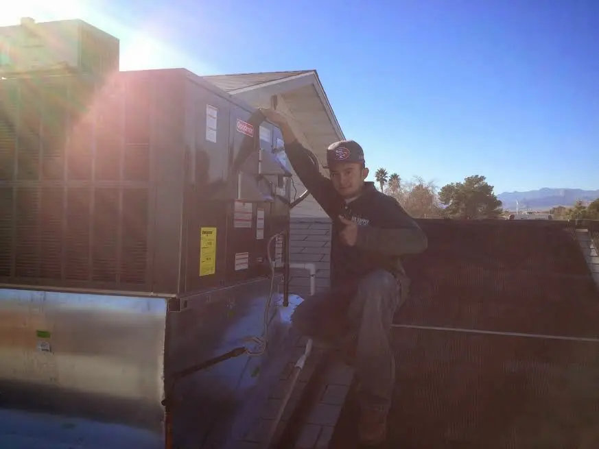 HVAC technician performing AC Tune-Up on a rooftop unit in Sheffield